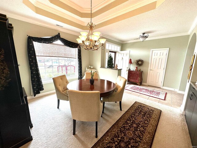 dining room with light carpet, ornamental molding, a textured ceiling, a chandelier, and a raised ceiling