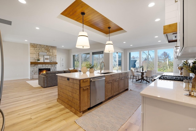 kitchen with dishwasher, light wood-type flooring, hanging light fixtures, and sink