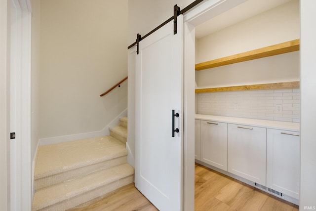 stairway with a barn door and hardwood / wood-style floors