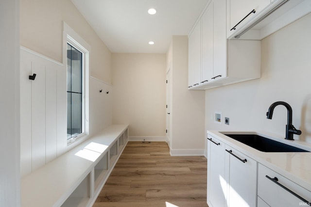 laundry room with hookup for an electric dryer, cabinets, sink, light hardwood / wood-style flooring, and hookup for a washing machine