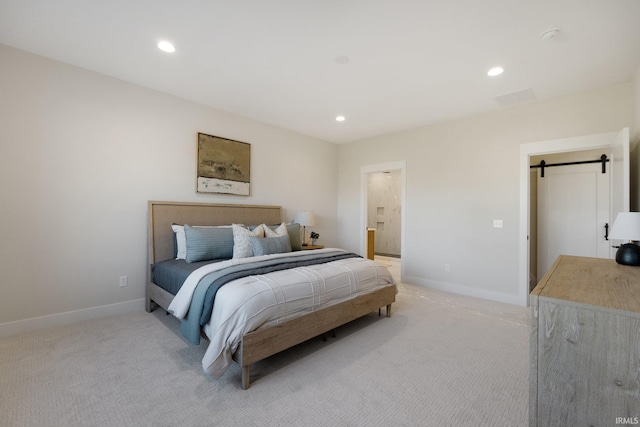 carpeted bedroom featuring a barn door and ensuite bath