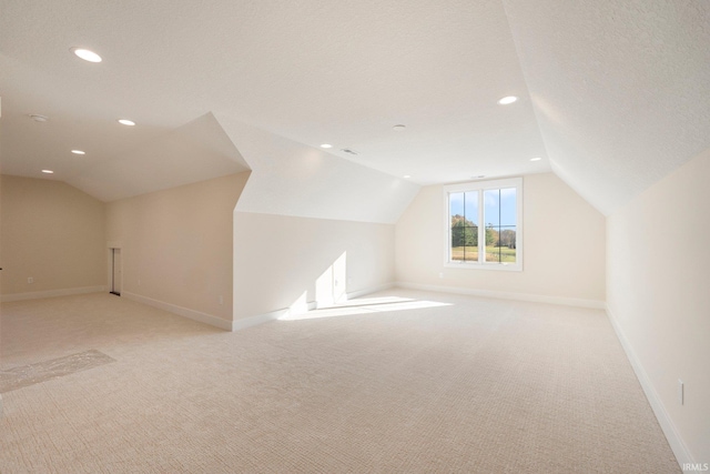 bonus room with lofted ceiling, a textured ceiling, and light carpet