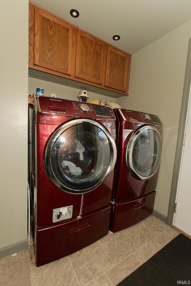 laundry area with cabinets, independent washer and dryer, and light tile patterned floors