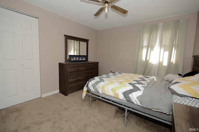 bedroom featuring ceiling fan, a textured ceiling, light carpet, and a closet