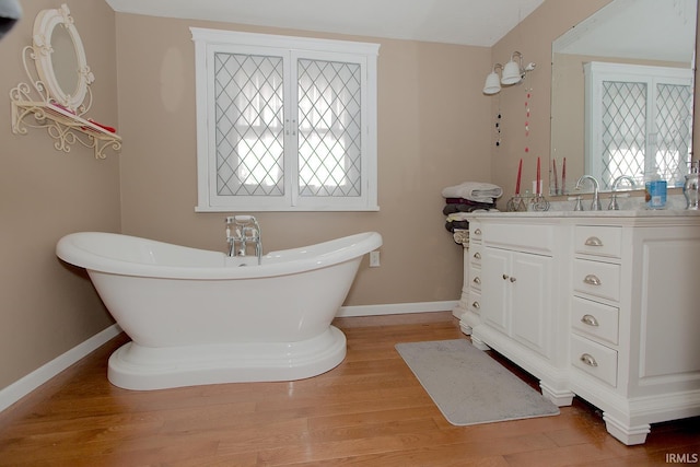 bathroom with a bathtub, vanity, a wealth of natural light, and hardwood / wood-style flooring