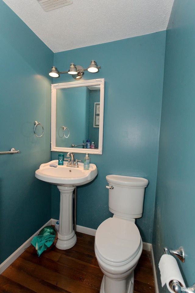 bathroom featuring wood-type flooring, a textured ceiling, and toilet