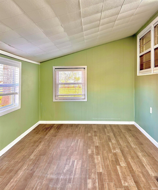 unfurnished room featuring a healthy amount of sunlight, lofted ceiling, and hardwood / wood-style flooring