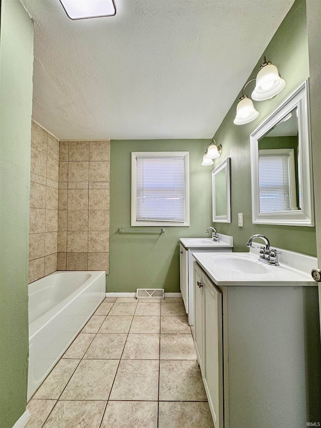 bathroom with a bath, a textured ceiling, tile patterned floors, and vanity