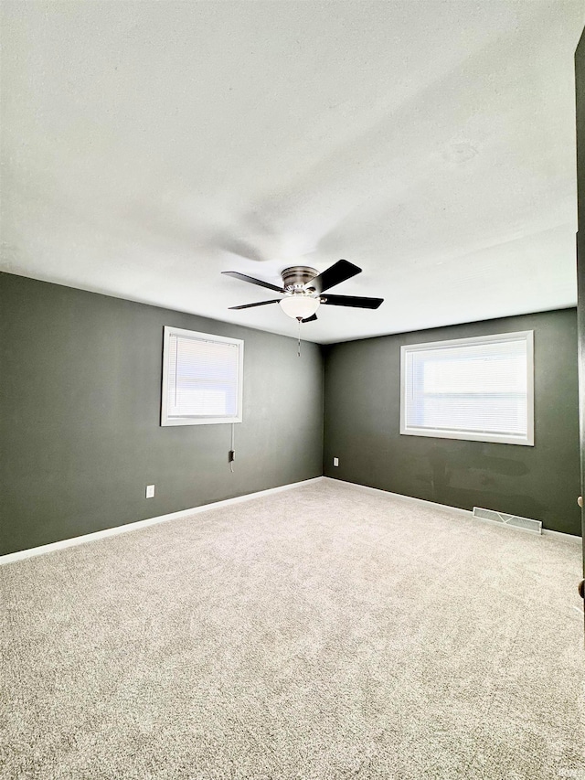 carpeted spare room with a textured ceiling, a healthy amount of sunlight, and ceiling fan