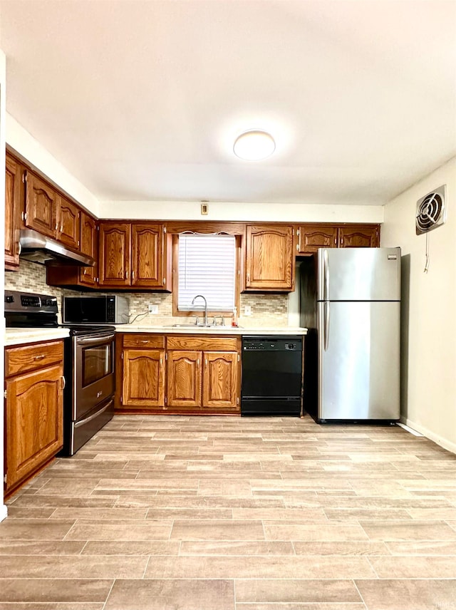 kitchen featuring tasteful backsplash, light wood-type flooring, appliances with stainless steel finishes, and sink