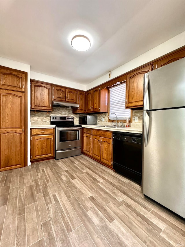 kitchen featuring stainless steel appliances, sink, light hardwood / wood-style flooring, and tasteful backsplash