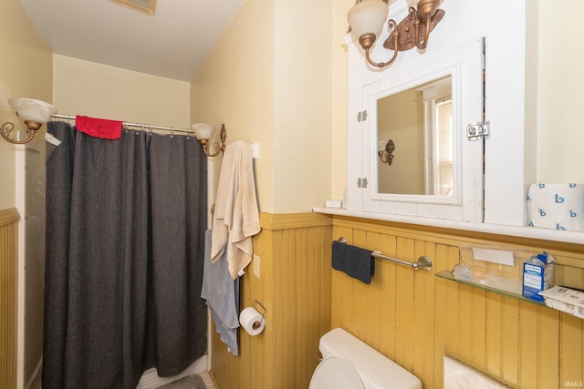 bathroom featuring toilet and wood walls