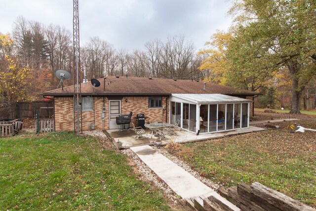 back of property with a patio area, a sunroom, and a yard