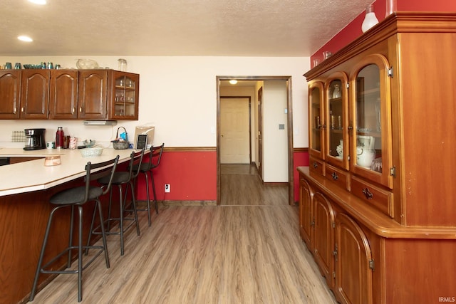 kitchen with a kitchen breakfast bar, light hardwood / wood-style floors, a textured ceiling, and kitchen peninsula