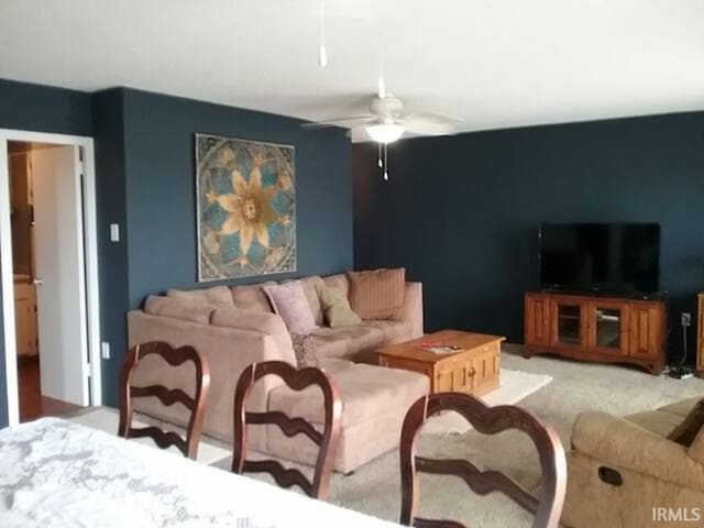 carpeted living room with ceiling fan