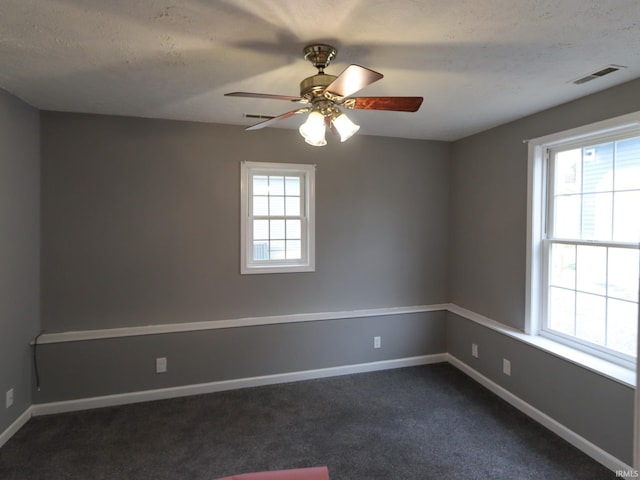 unfurnished room with ceiling fan, dark colored carpet, and a textured ceiling