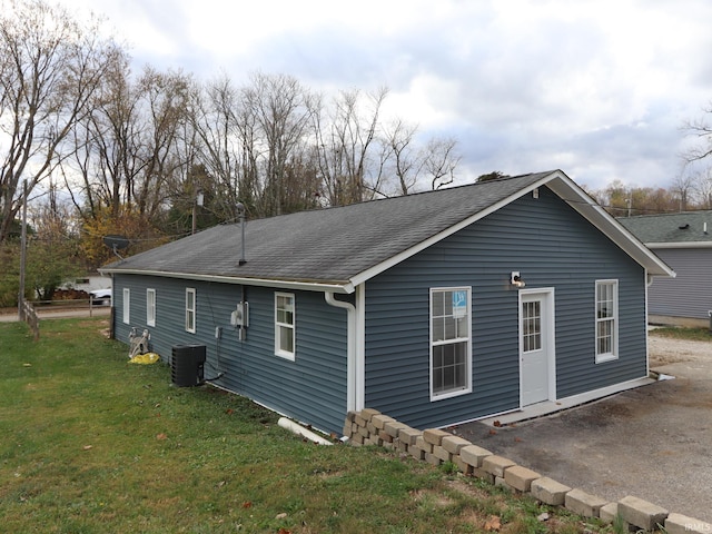 view of side of home with a lawn and central AC