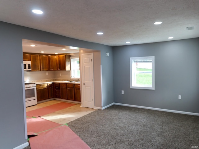 kitchen with white appliances, sink, and light colored carpet