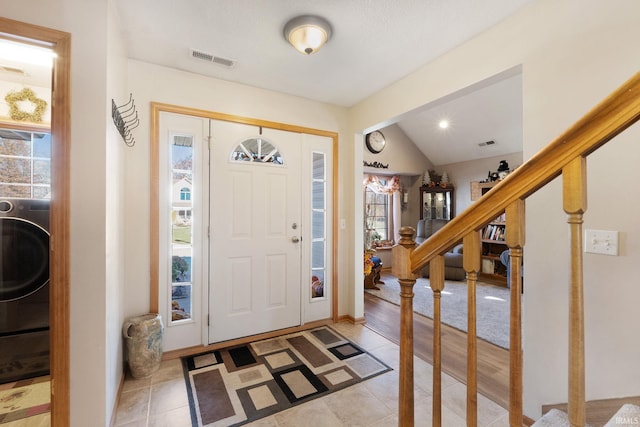 foyer entrance featuring washer / clothes dryer, lofted ceiling, and light hardwood / wood-style flooring