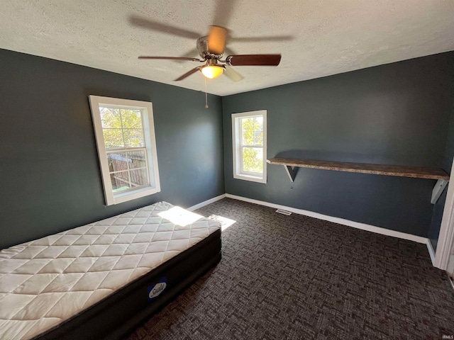 carpeted bedroom with multiple windows, a textured ceiling, and ceiling fan