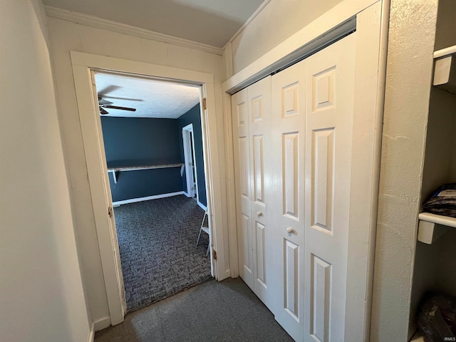 corridor featuring dark colored carpet and crown molding