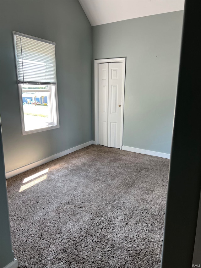 unfurnished room with vaulted ceiling and carpet