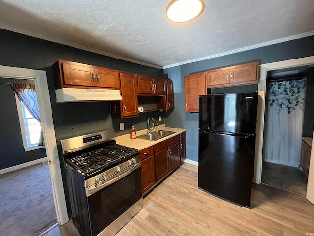 kitchen featuring stainless steel gas range oven, black refrigerator, sink, and light hardwood / wood-style floors