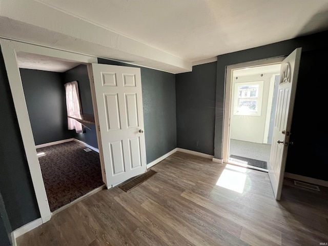 unfurnished bedroom with multiple windows and hardwood / wood-style flooring