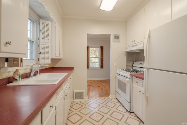 kitchen with white cabinets, plenty of natural light, and white appliances