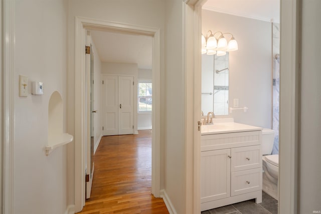 bathroom featuring toilet, vanity, hardwood / wood-style floors, and ornamental molding