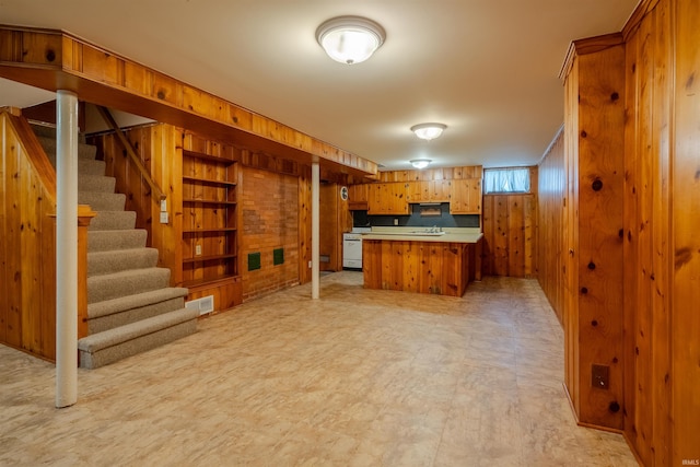 kitchen featuring kitchen peninsula, wooden walls, sink, and white range