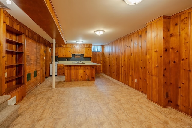 kitchen featuring wooden walls, sink, white range, and a center island