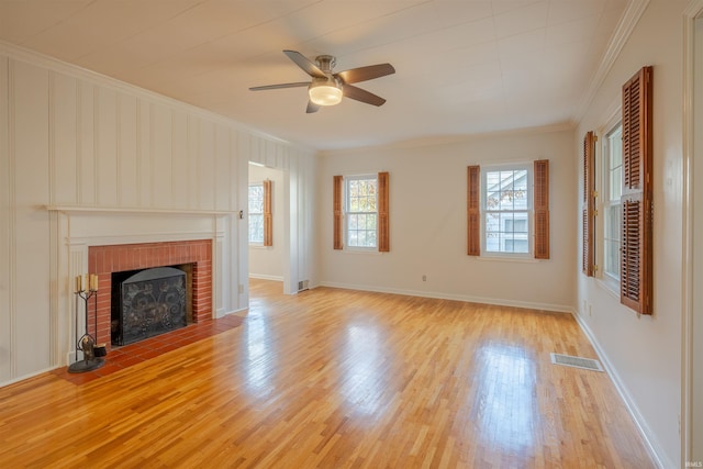 unfurnished living room with ornamental molding, light wood-type flooring, a brick fireplace, and ceiling fan