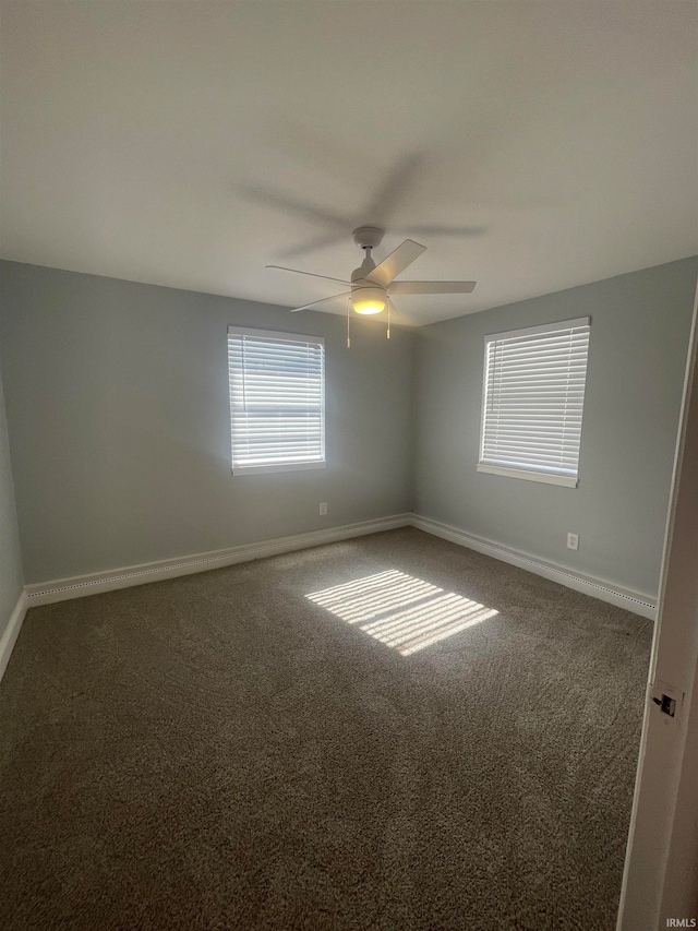 empty room with ceiling fan and dark colored carpet