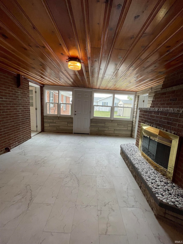 unfurnished living room featuring a fireplace, wood ceiling, and plenty of natural light