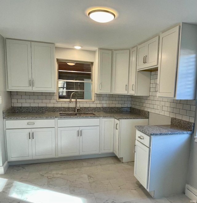 kitchen featuring decorative backsplash, white cabinetry, sink, and a baseboard heating unit