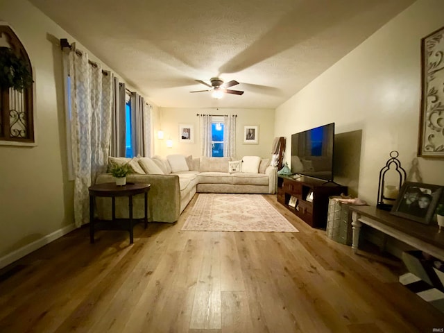 living room featuring ceiling fan, a textured ceiling, and light hardwood / wood-style floors