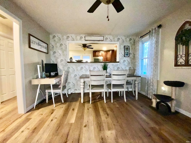 dining room with wood-type flooring, ceiling fan, and a textured ceiling