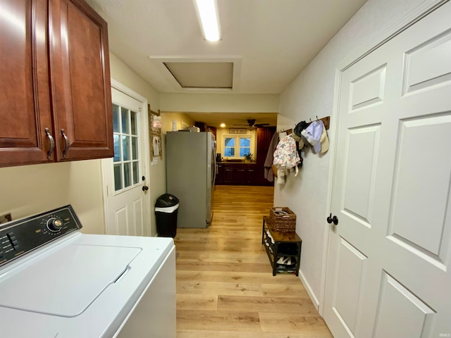 clothes washing area with cabinets, light hardwood / wood-style floors, and washer / clothes dryer