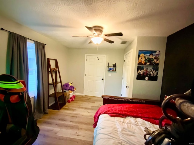 bedroom with a textured ceiling, light wood-type flooring, and ceiling fan