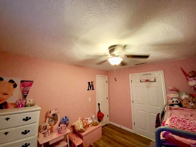 bedroom with dark wood-type flooring, ceiling fan, and a textured ceiling