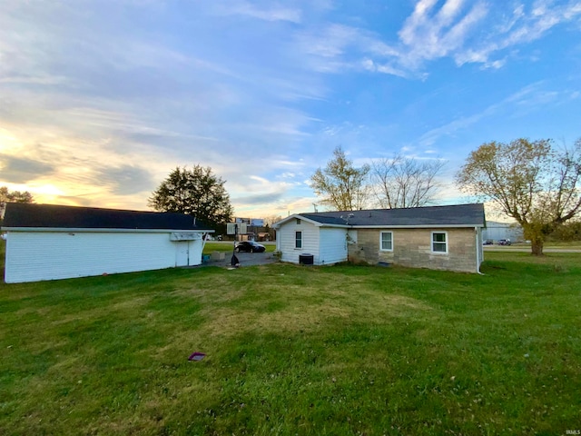 back house at dusk with a lawn