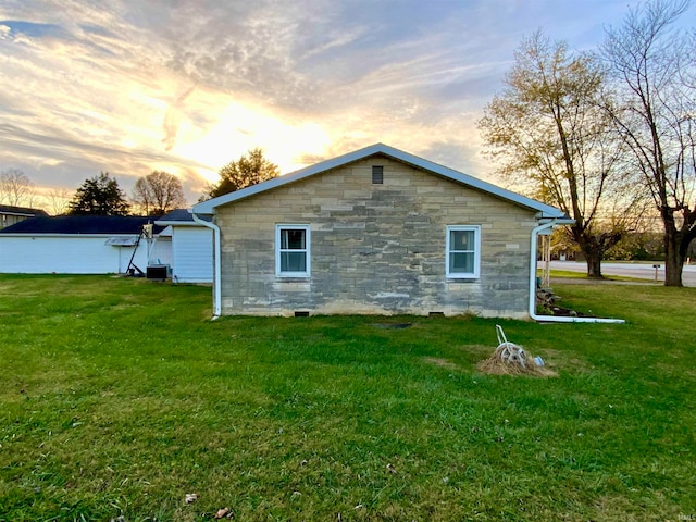 property exterior at dusk featuring central AC and a yard