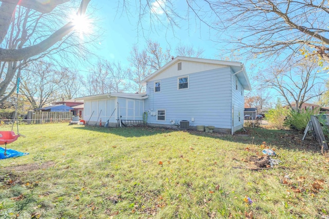 rear view of property featuring cooling unit and a yard