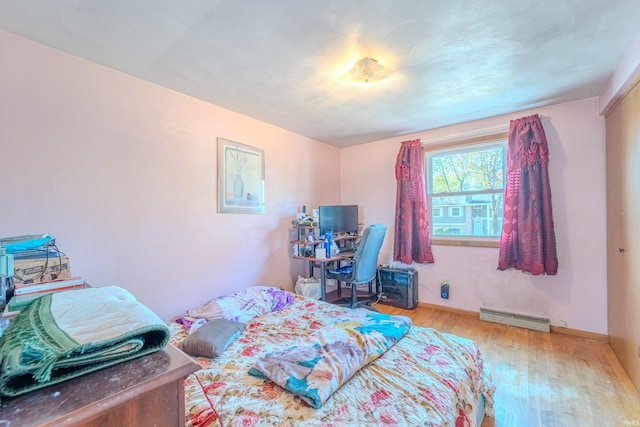 bedroom with light hardwood / wood-style floors and a baseboard radiator