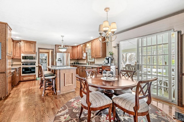 dining area with a chandelier, sink, and light hardwood / wood-style flooring