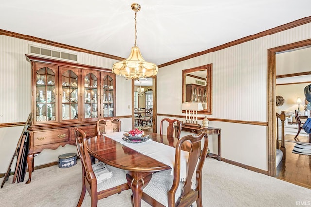 dining room featuring ornamental molding, light wood-type flooring, and a chandelier