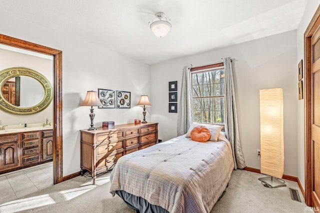 bedroom with ensuite bathroom and light colored carpet