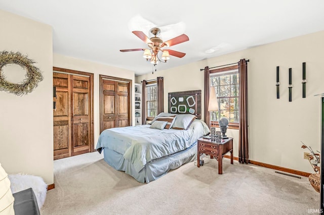 bedroom with carpet, two closets, and ceiling fan