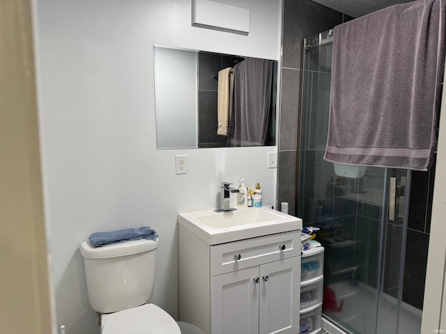 bathroom with a shower with door, vanity, and toilet